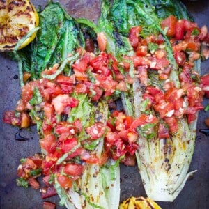 Grilled Romaine Lettuce on a platter topped with Tomatoes and Basil and Balsamic