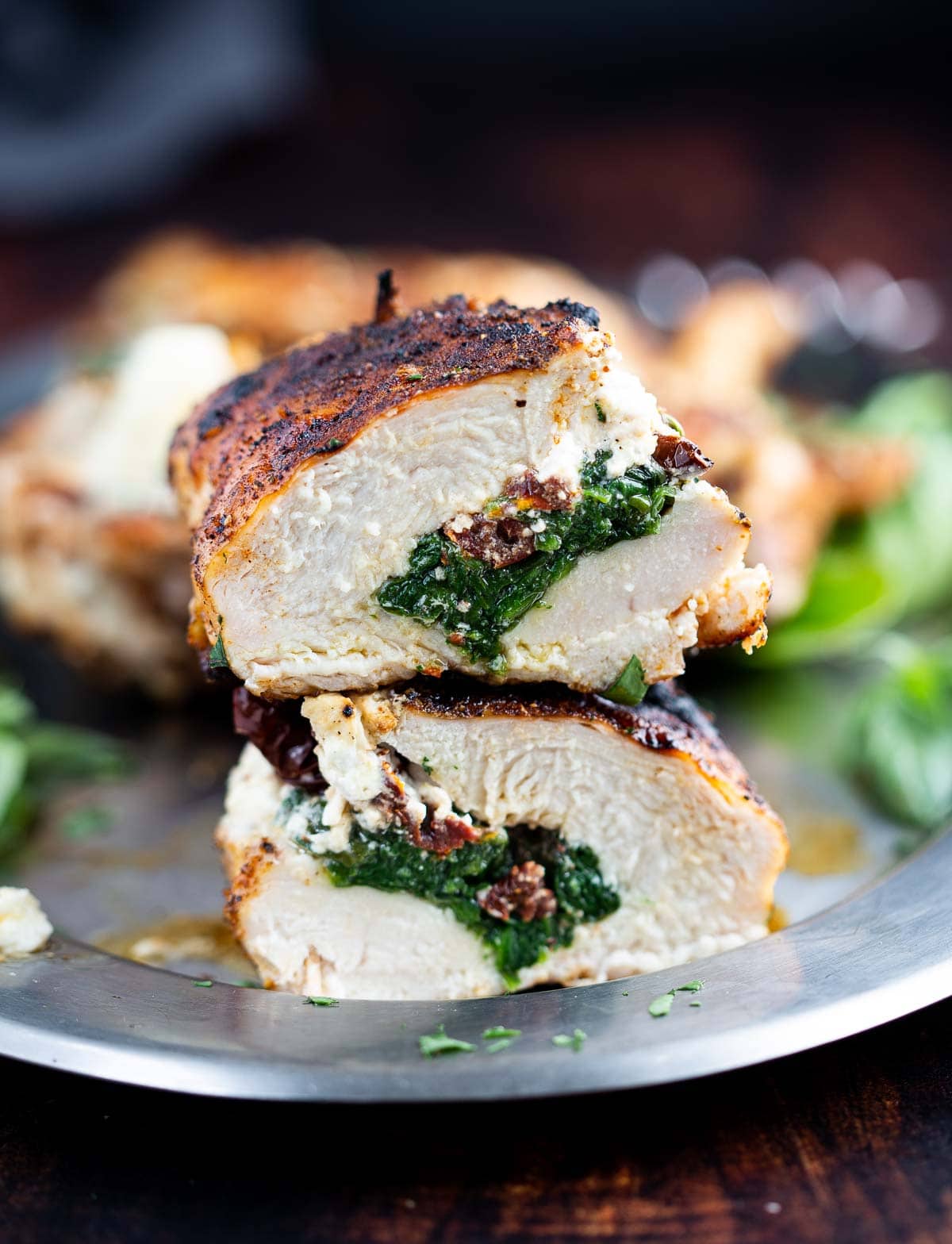 Two halves of grilled chicken breasts stuffed with goat cheese, spinach, and sun-dried tomatoes