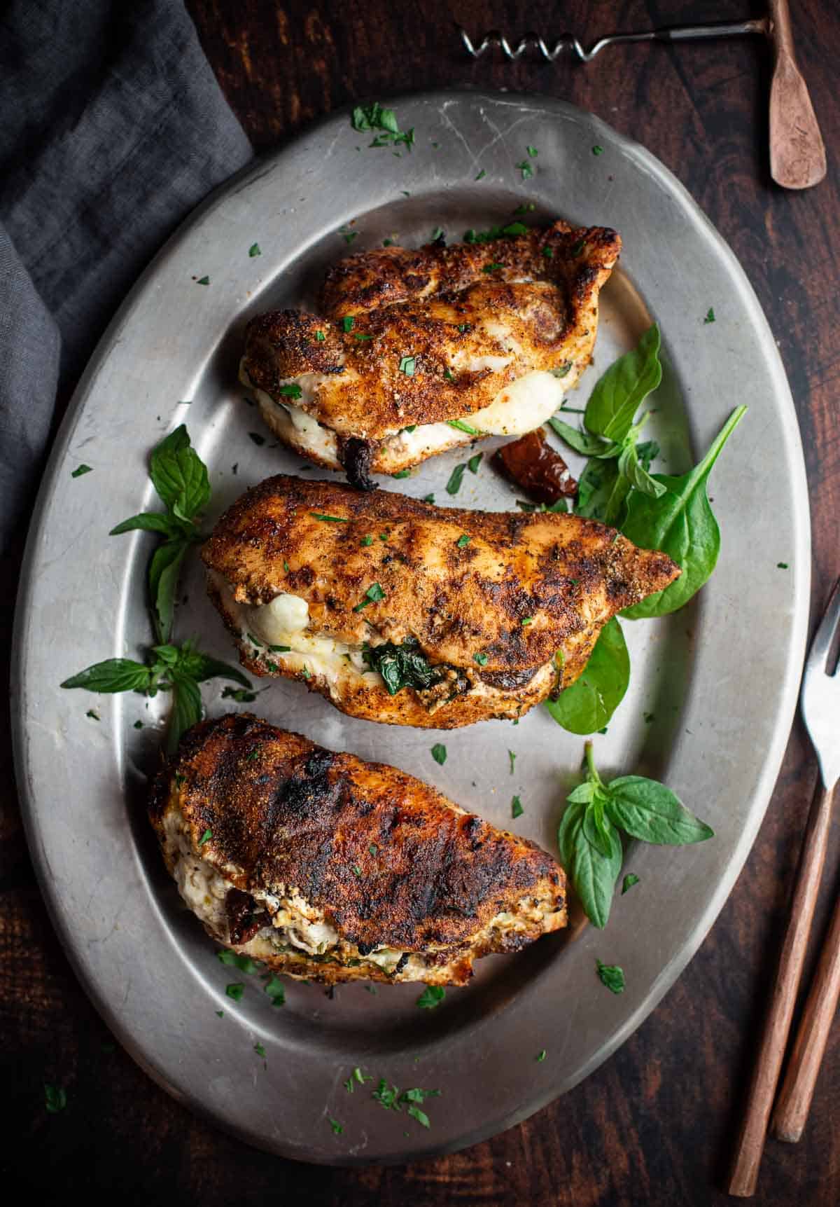 Grilled Stuffed Chicken Breasts on a platter with spinach and sun dried tomatoes