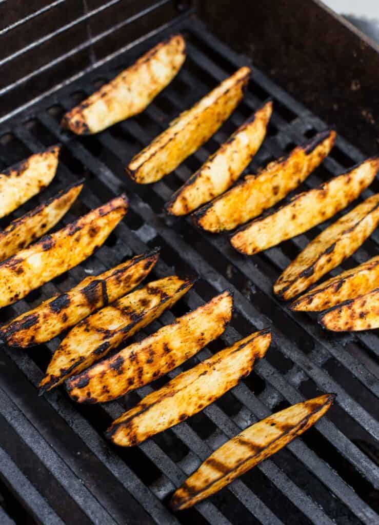 Grilled potato wedges over direct heat with grill marks.