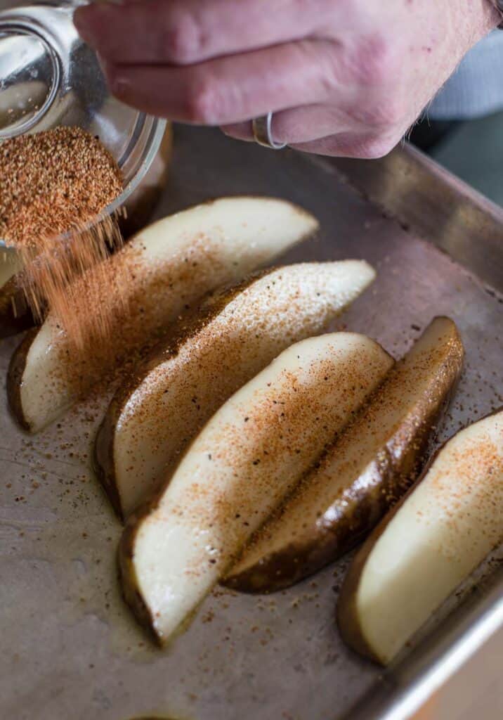 Seasoning potato wedges about to go on the grill.