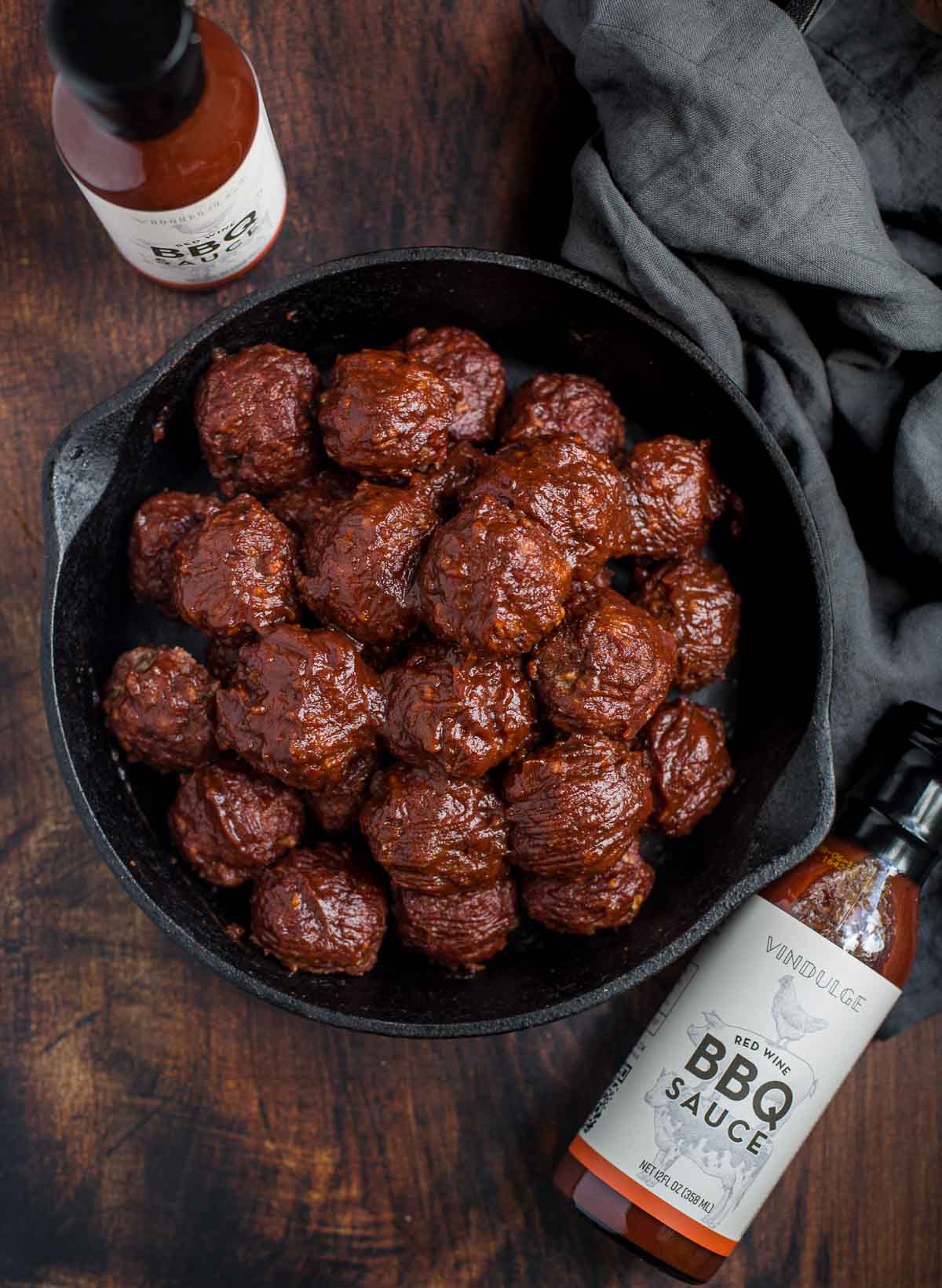 Smoked Meatballs with Red Wine BBQ Sauce in a serving pan with a bottle of Vindulge BBQ Sauce