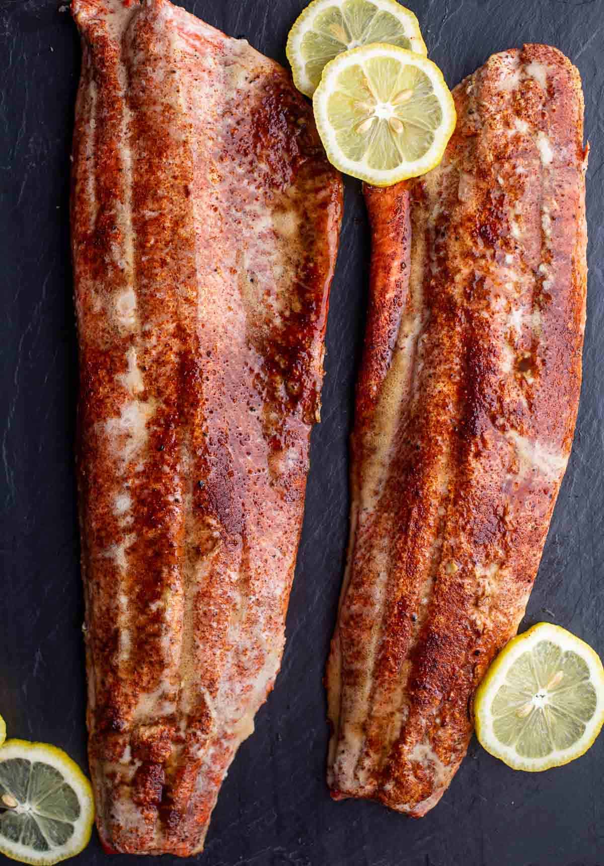 Two filets of perfect Smoked Sockeye Salmon on a serving dish with slices of lemon 