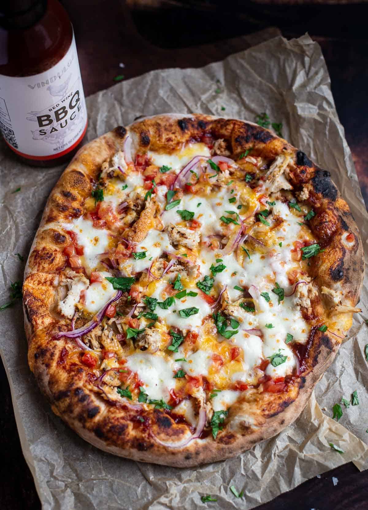 A BBQ Chicken Pizza with a bottle of Vindulge Red Wine BBQ Sauce