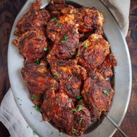 Grilled Boneless Chicken Thighs on a platter coated with Vindulge Red Wine BBQ Sauce