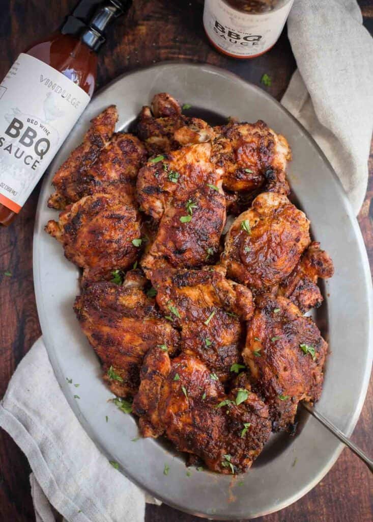 Grilled Boneless Skinless Chicken Thighs on a platter with Vindulge Red Wine BBQ Sauce