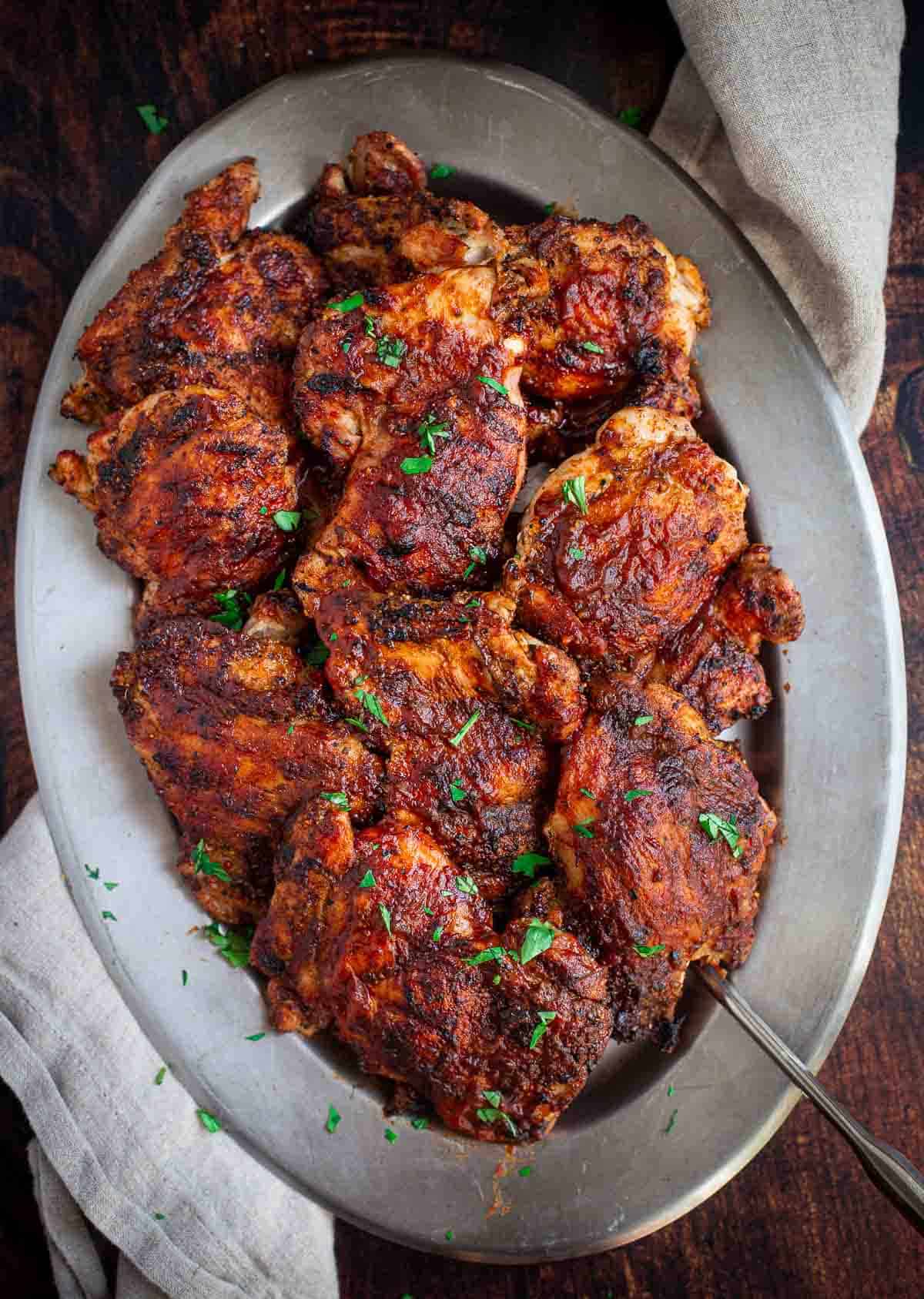 Grilled Boneless Skinless Chicken Thighs on a platter topped with Vindulge BBQ Sauce