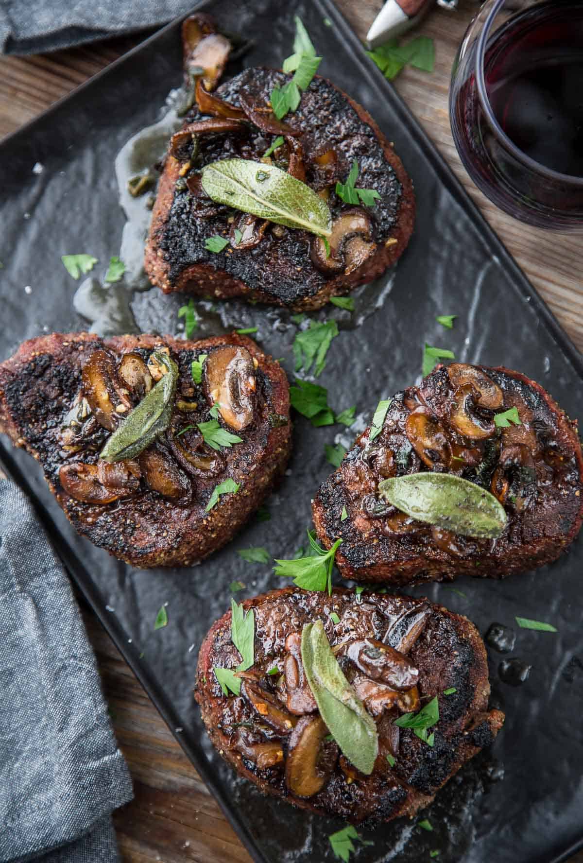 Grilled Filet Mignon steaks topped with with Mushroom Brown Butter sauce on a platter.