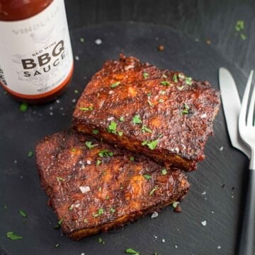 Grilled Tofu steaks topped with BBQ Sauce with a jar of Vindulge Red Wine BBQ Sauce on a platter