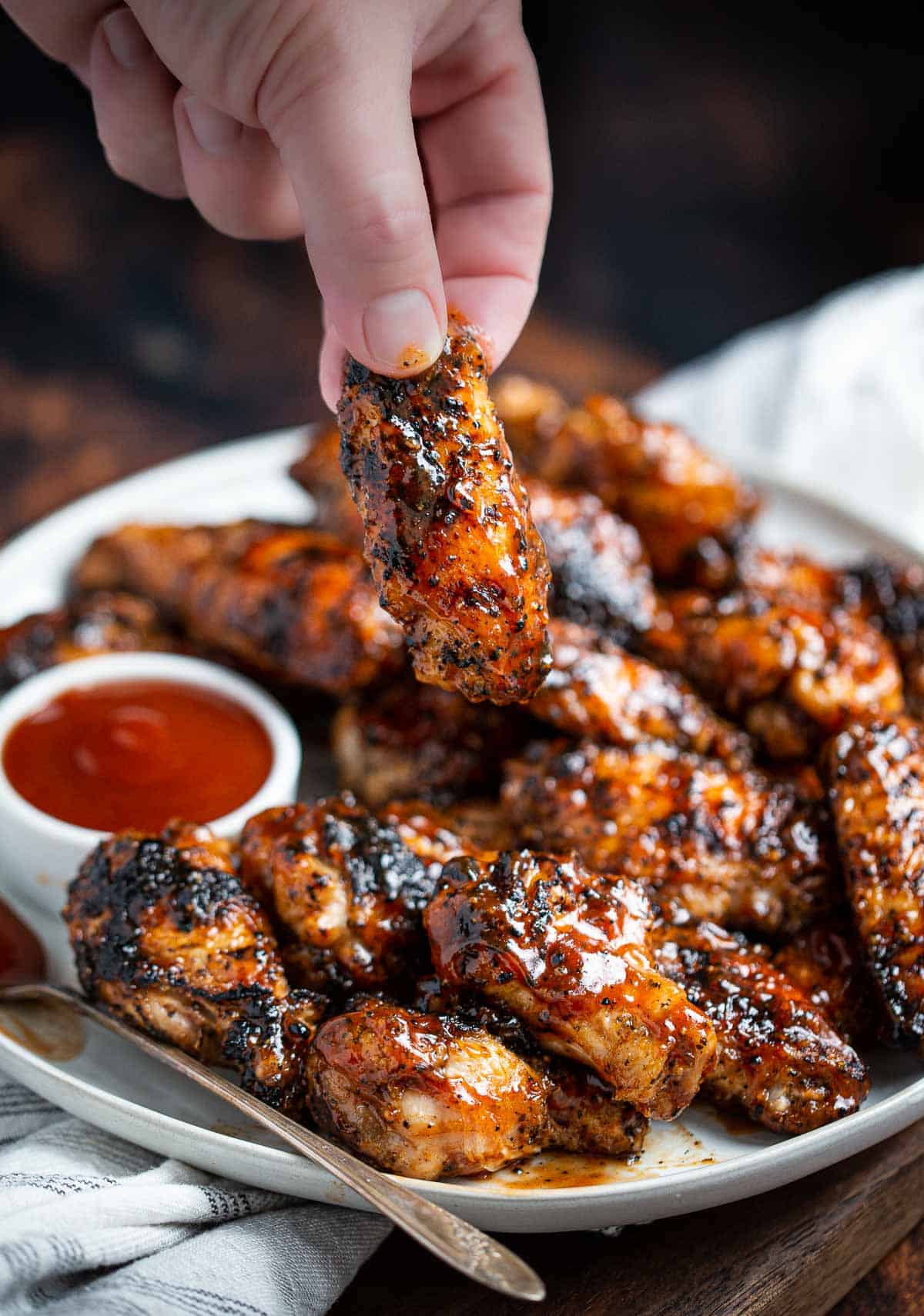 A hand holding a Grilled Honey Bourbon Chicken Wing