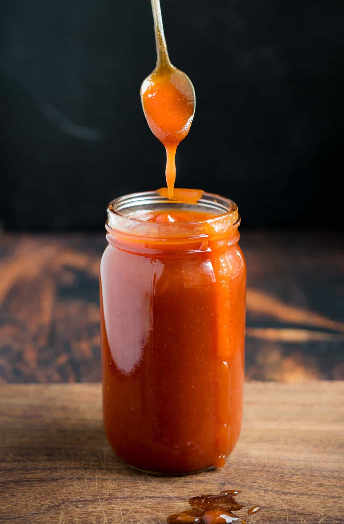 Honey Bourbon BBQ Sauce in a jar with a spoon dipping into it 