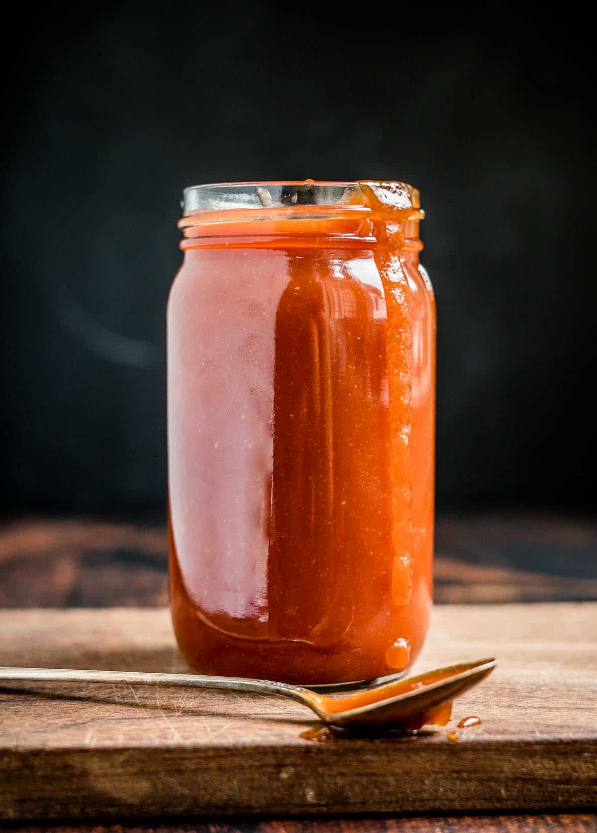 Honey Bourbon BBQ Sauce in a mason jar with a spoon dripping with sauce