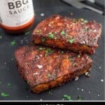 Two grilled and glazed pieces of tofu on a slate plate.