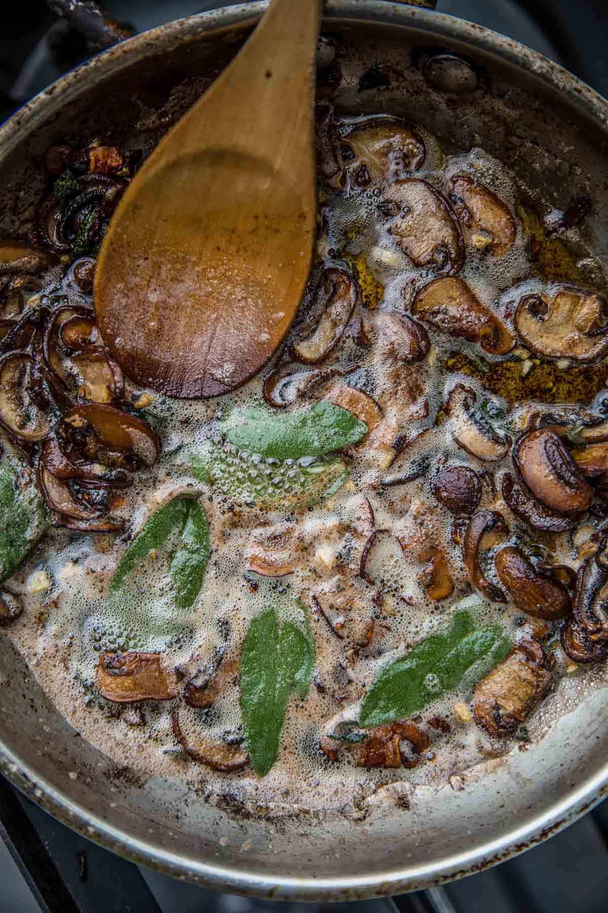 A mushroom brown butter and sage pan sauce cooking in a skillet.