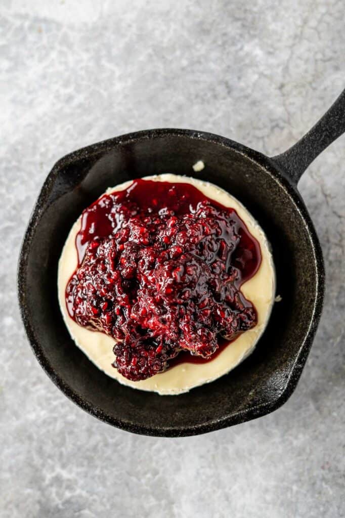 brie topped with blackberry jam in a cast iron pan