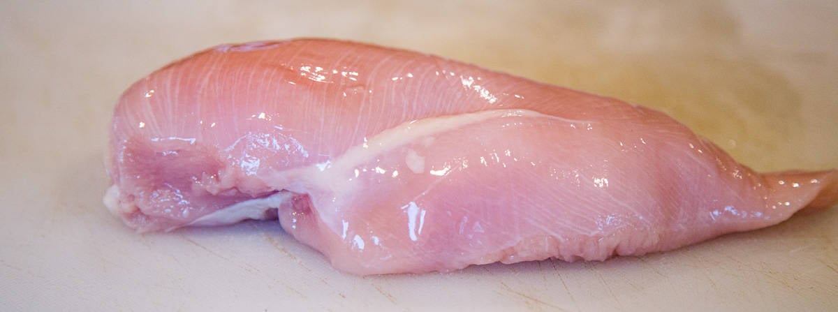 a raw chicken breast on a cutting board