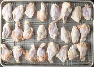 Chicken wing flat and drums on a sheet tray lined with a wire rack.