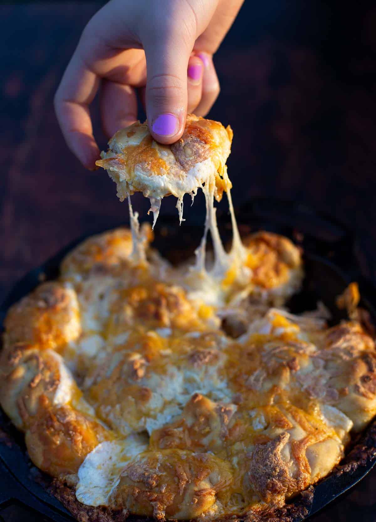 Grilled Buffalo Chicken Pull Apart Bread in a cast iron pan with a cheese pull