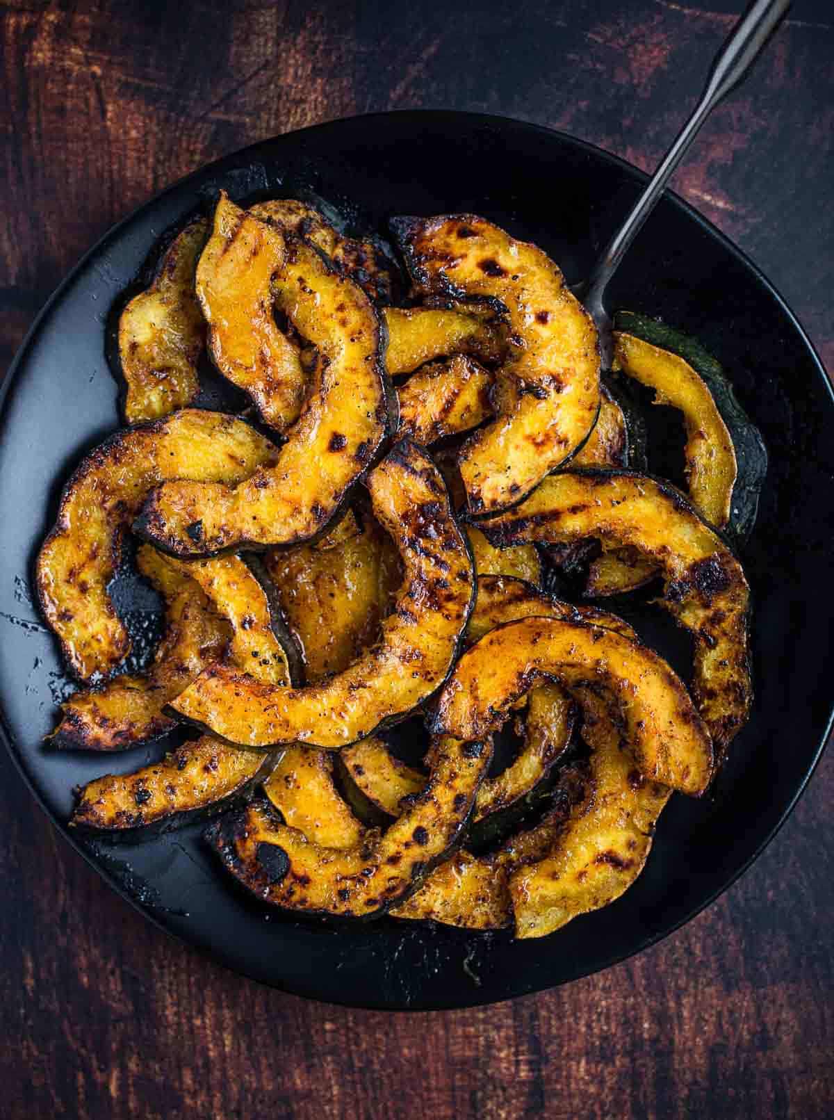 Grilled Acorn Squash topped with a maple glaze on a serving dish 