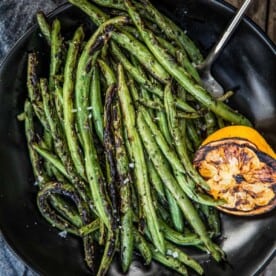 Grilled Green Beans on a platter with a side of grilled lemons