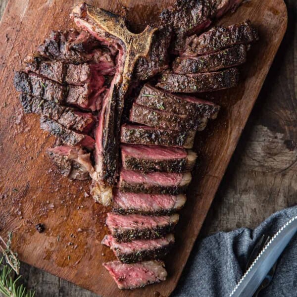 A grilled T Bone Steak sliced up on a cutting board