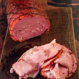 A smoked Mortadella and slices of mortadella on a cutting board