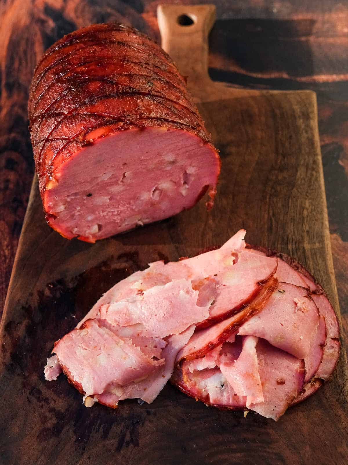 Smoked mortadella and slices of mortadella on a cutting board