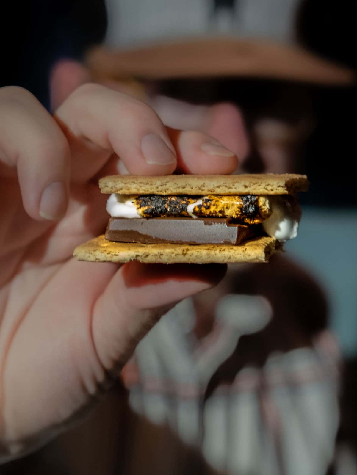 Sean Martin from Vindulge holding a s'more made with chocolate and roasted marshmallows