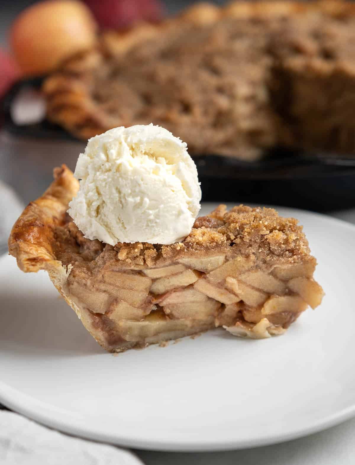 A slice of Grilled Apple Pie on a plate next to a Dutch Apple Pie