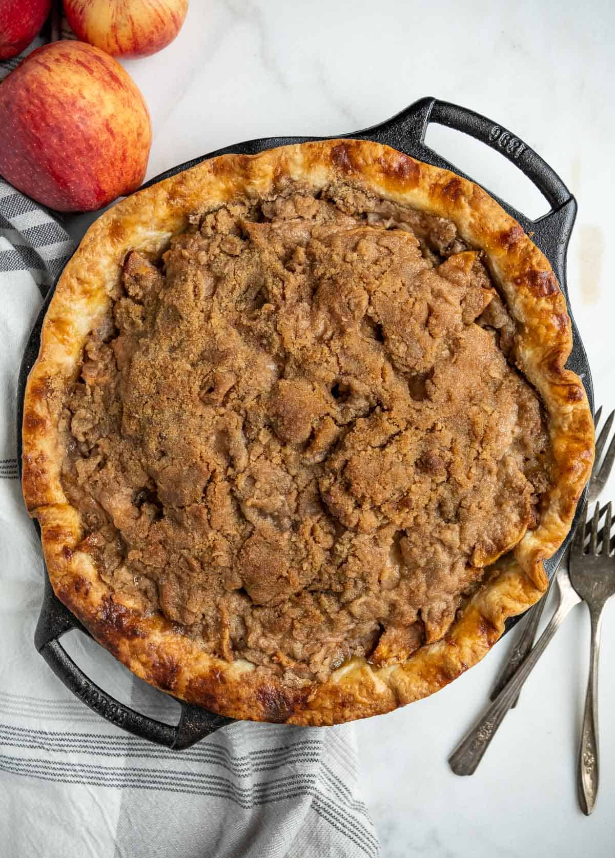Grilled apple pie in cast iron pie pan on a board.