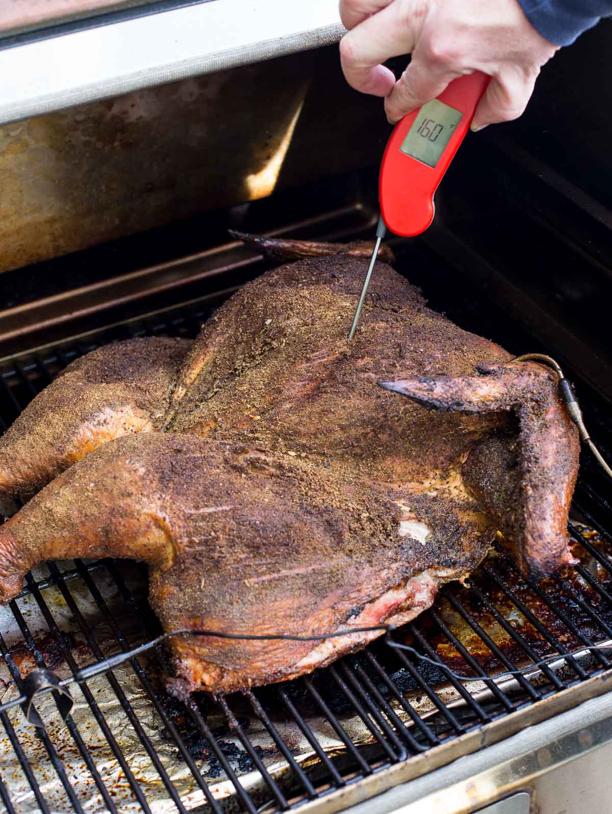 Taking the temperautre of a spatchcocked turkey with the Thermapen One on a pellet grill.