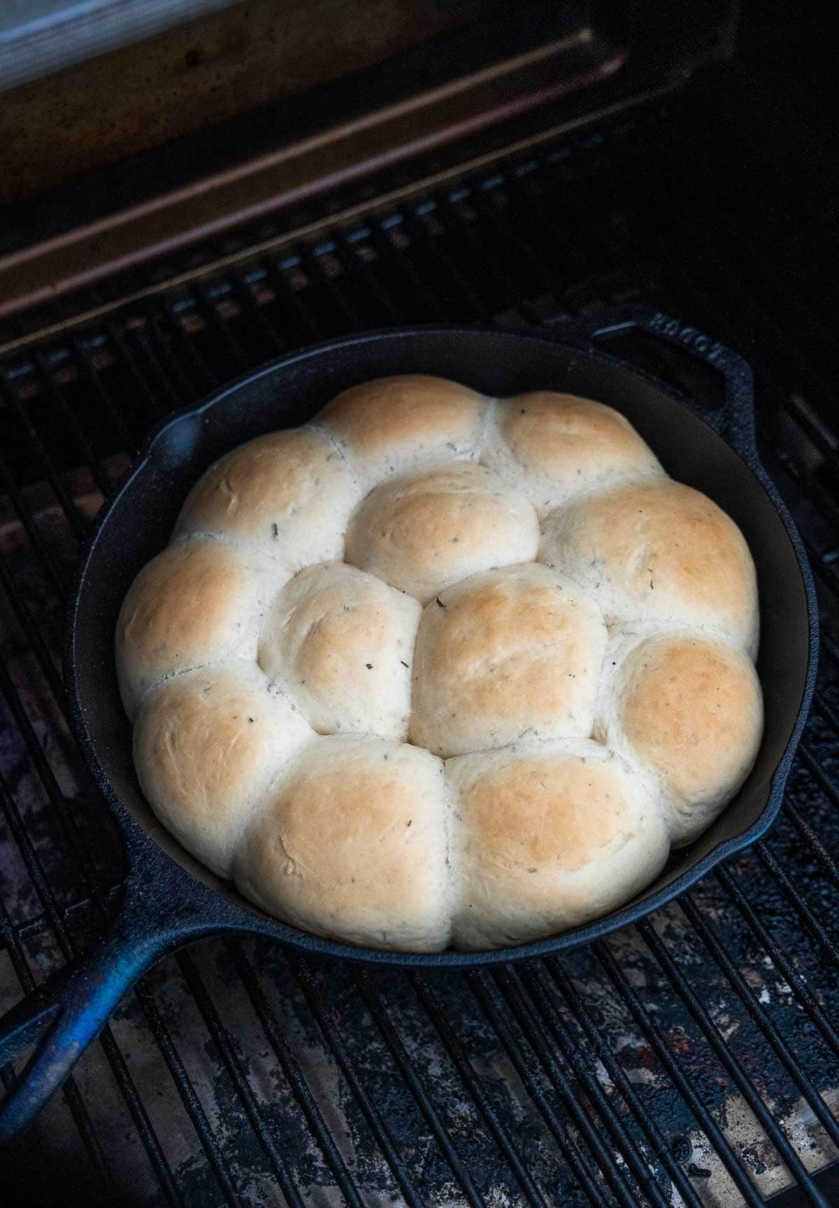 Cast Iron dinner rolls grilling over indirect heat in a pellet grill.