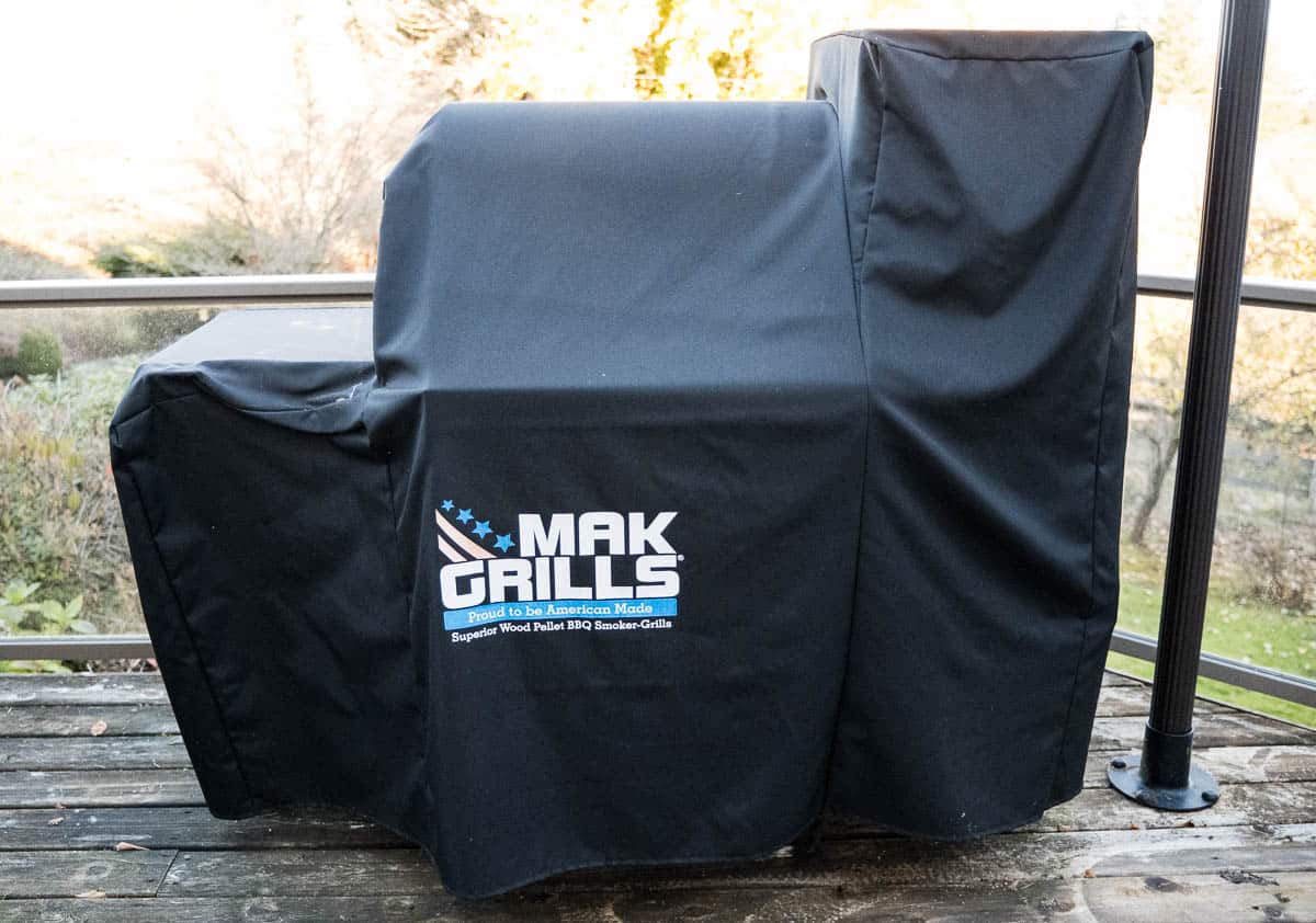 A pellet grill with a winter protection cover over it