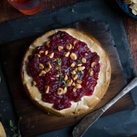 Grilled brie with cranberry jam and hazelnuts on a plank and serving plate.