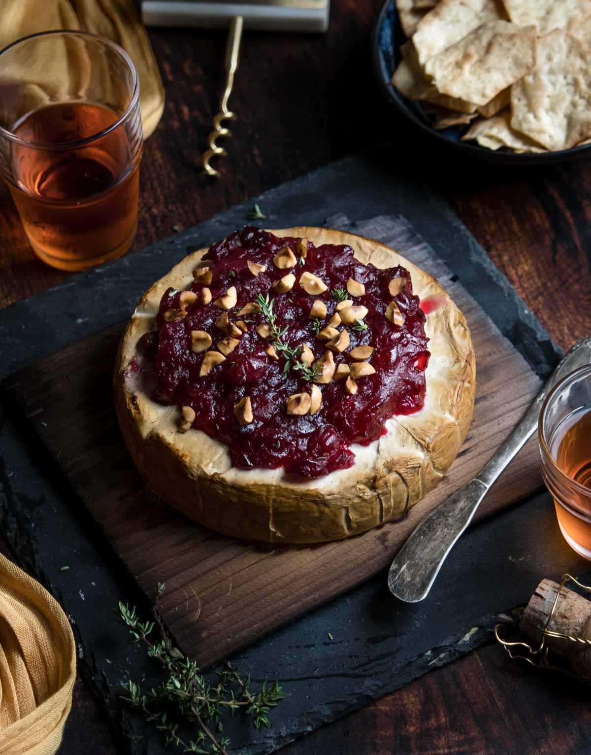 Cedar Plank Brie with Cranberry Sauce on a serving platter topped with toasted hazelnuts