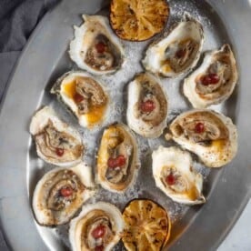 BBQ Oysters on a serving platter served with some red wine bbq sauce and grilled lemon