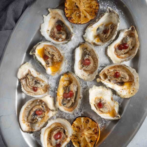 BBQ Oysters on a serving platter served with some red wine bbq sauce and grilled lemon