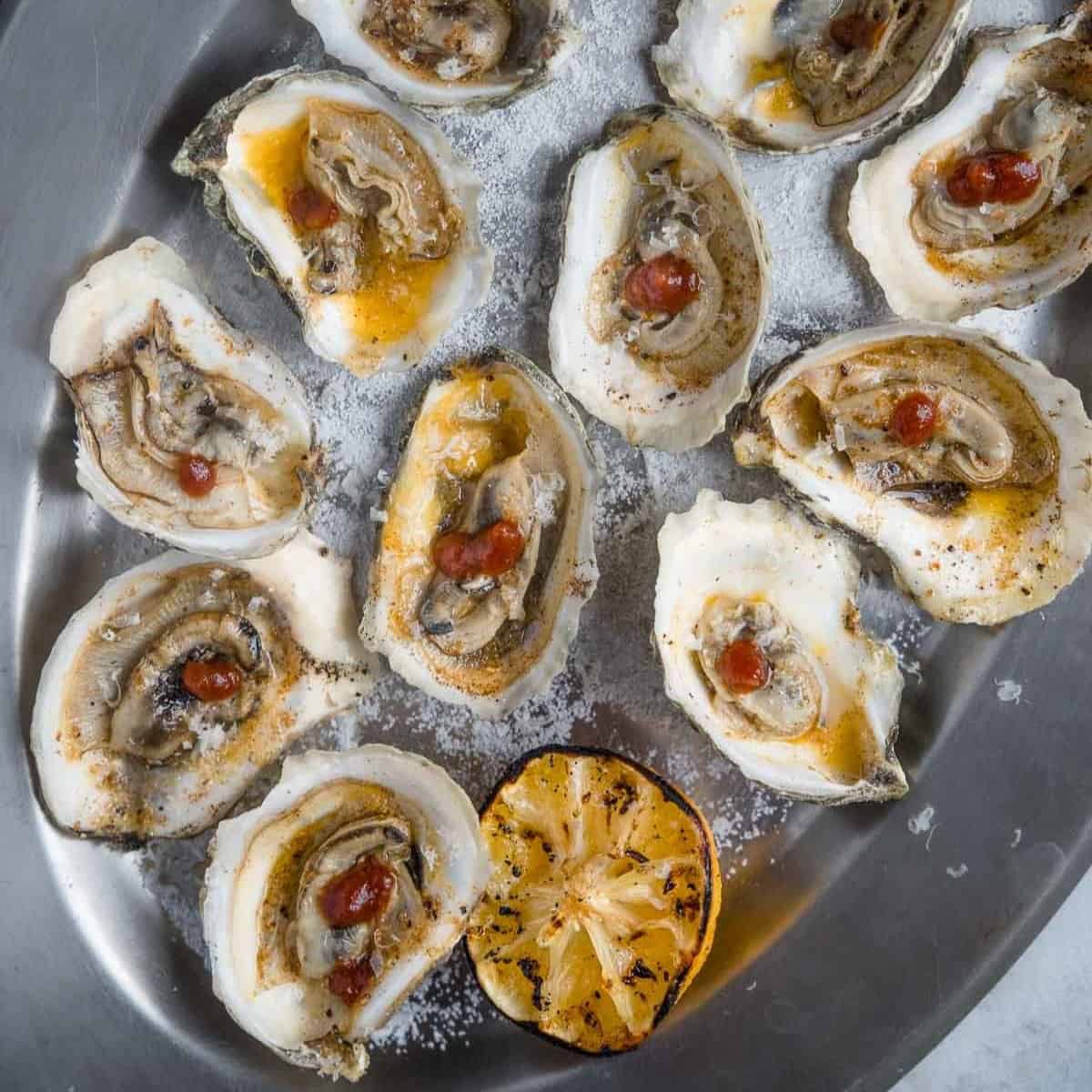 BBQ oysters on a serving platter with grilled lemon.