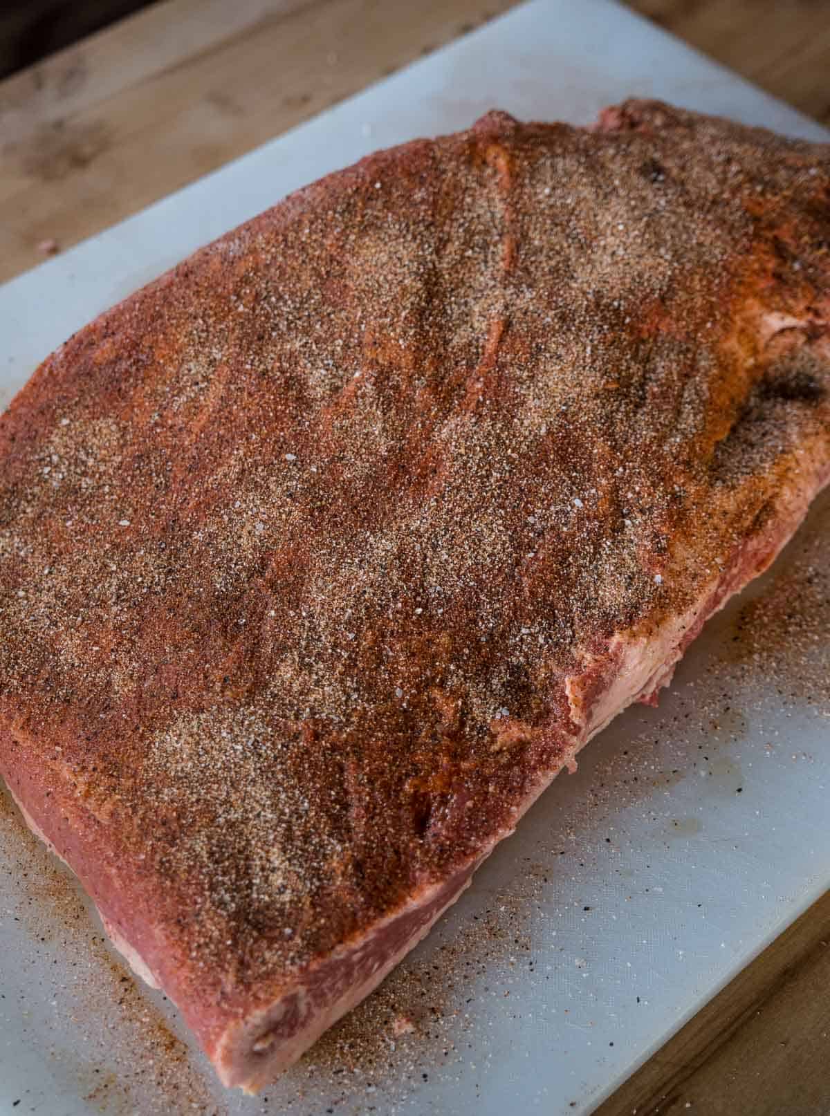 A seasoned and trimmed brisket on a sheet tray.
