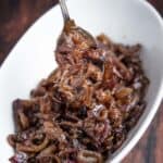 Caramelized onions in a bowl being lifted out with a spoon.