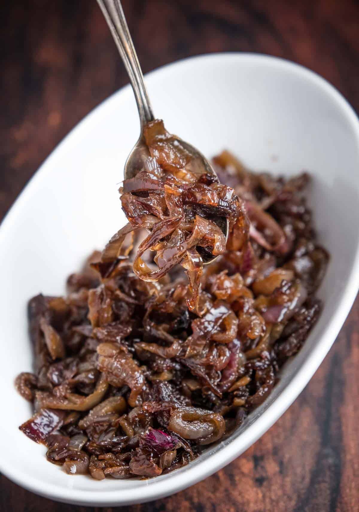 Caramelized onions on a spoon over a serving dish