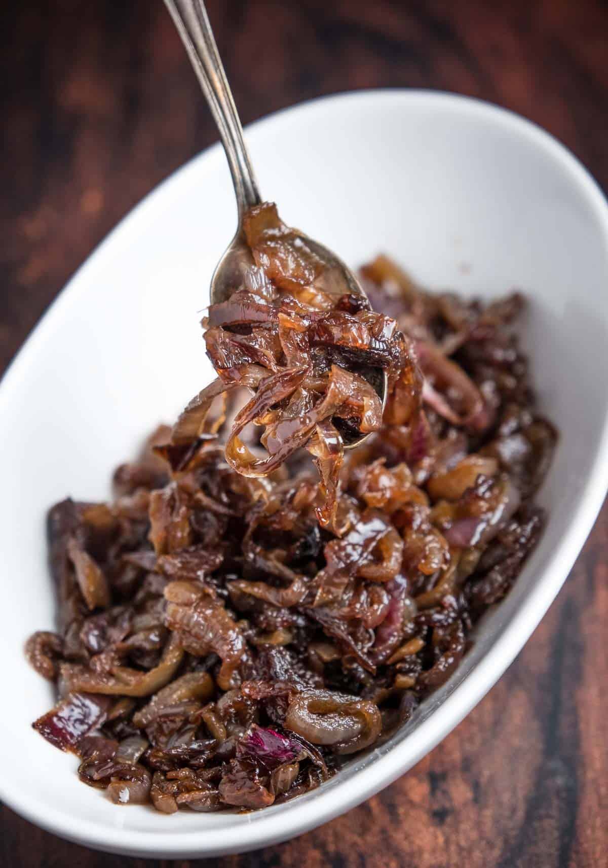 Caramelized onions in a bowl being lifted out with a spoon.