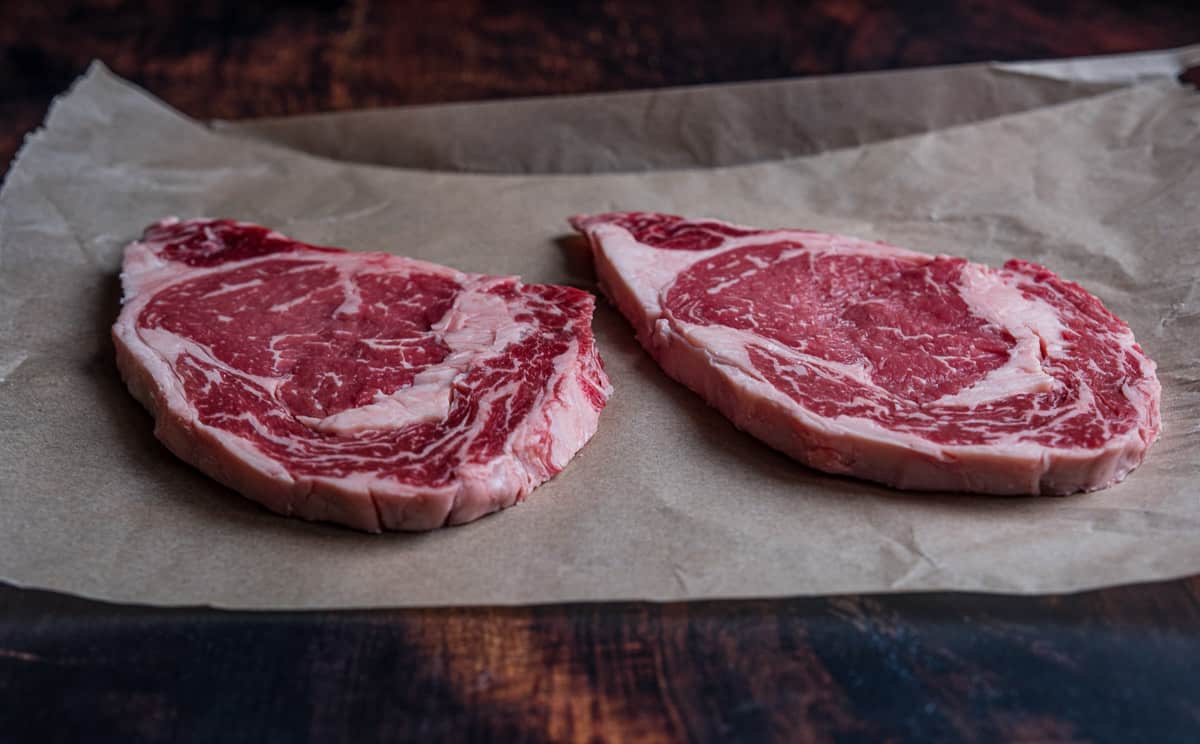 two raw thin ribeye steaks