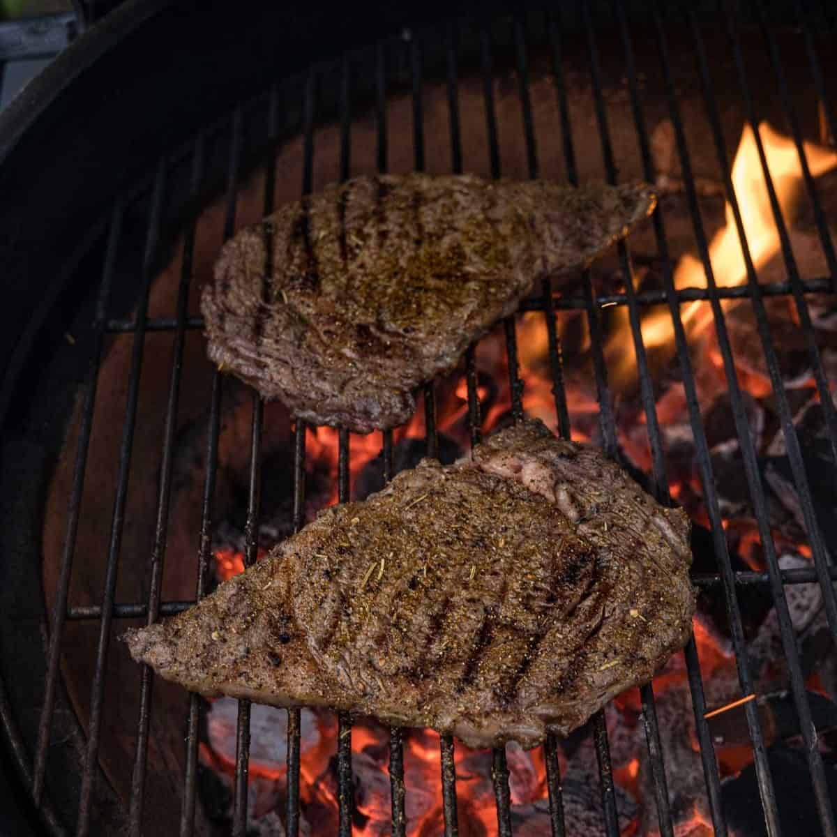 2 Thin steaks on a grill over direct heat.