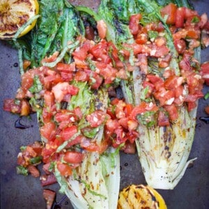 Grilled romaine lettuce topped with tomatoes and basil