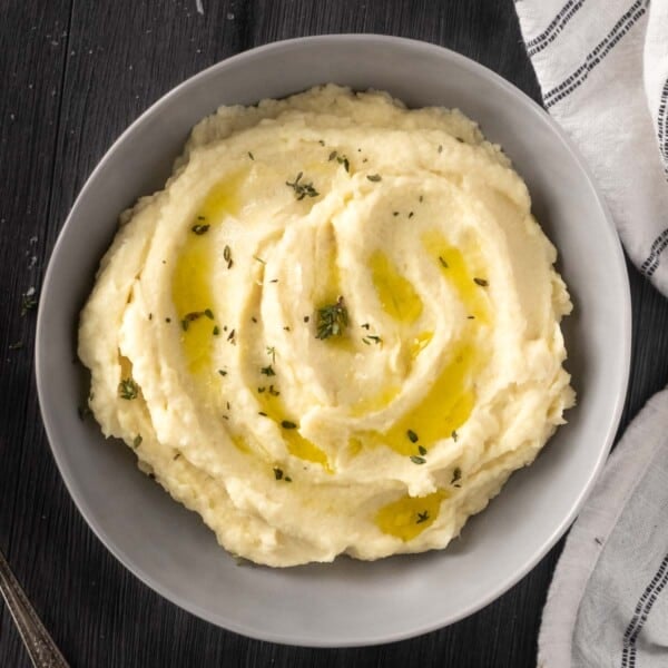 Parsnip puree in a bowl topped with melted butter and thyme.