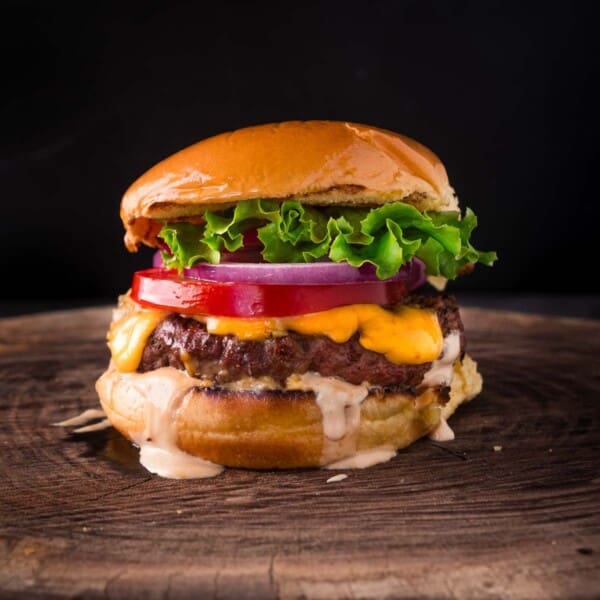 Classic American smoked hamburger with cheese on a cutting board.