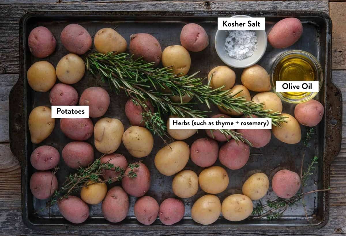 Ingredients for crispy roasted breakfast potatoes on a sheet pan overlayed with text ingredient names. 