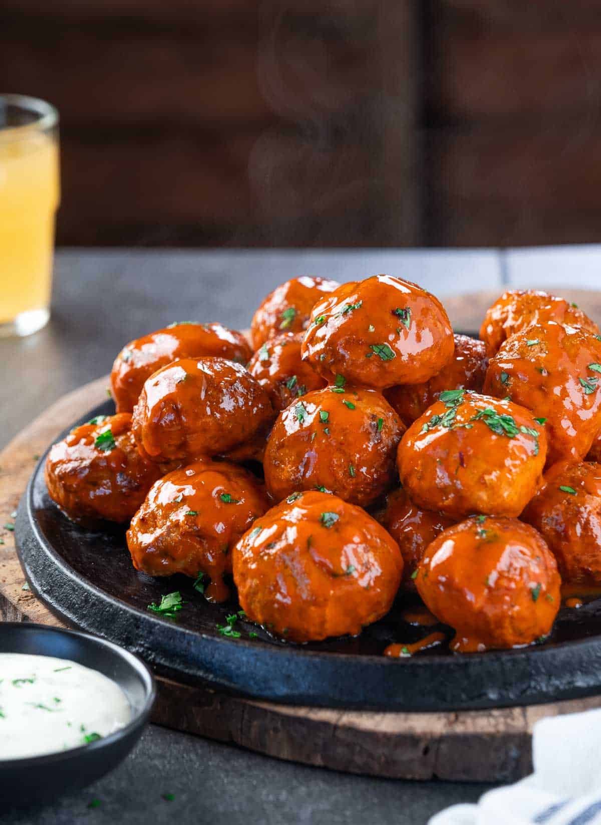 Smoked Buffalo Chicken meatballs with ranch and a beer on a platter.