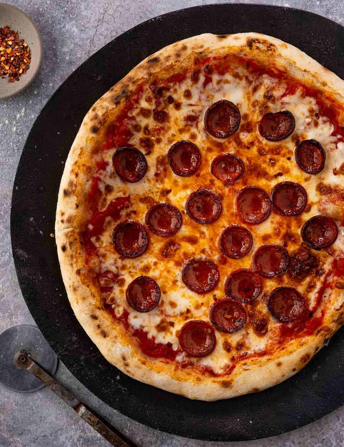 A pepperoni pizza made with a Sourdough Pizza Dough on a serving platter